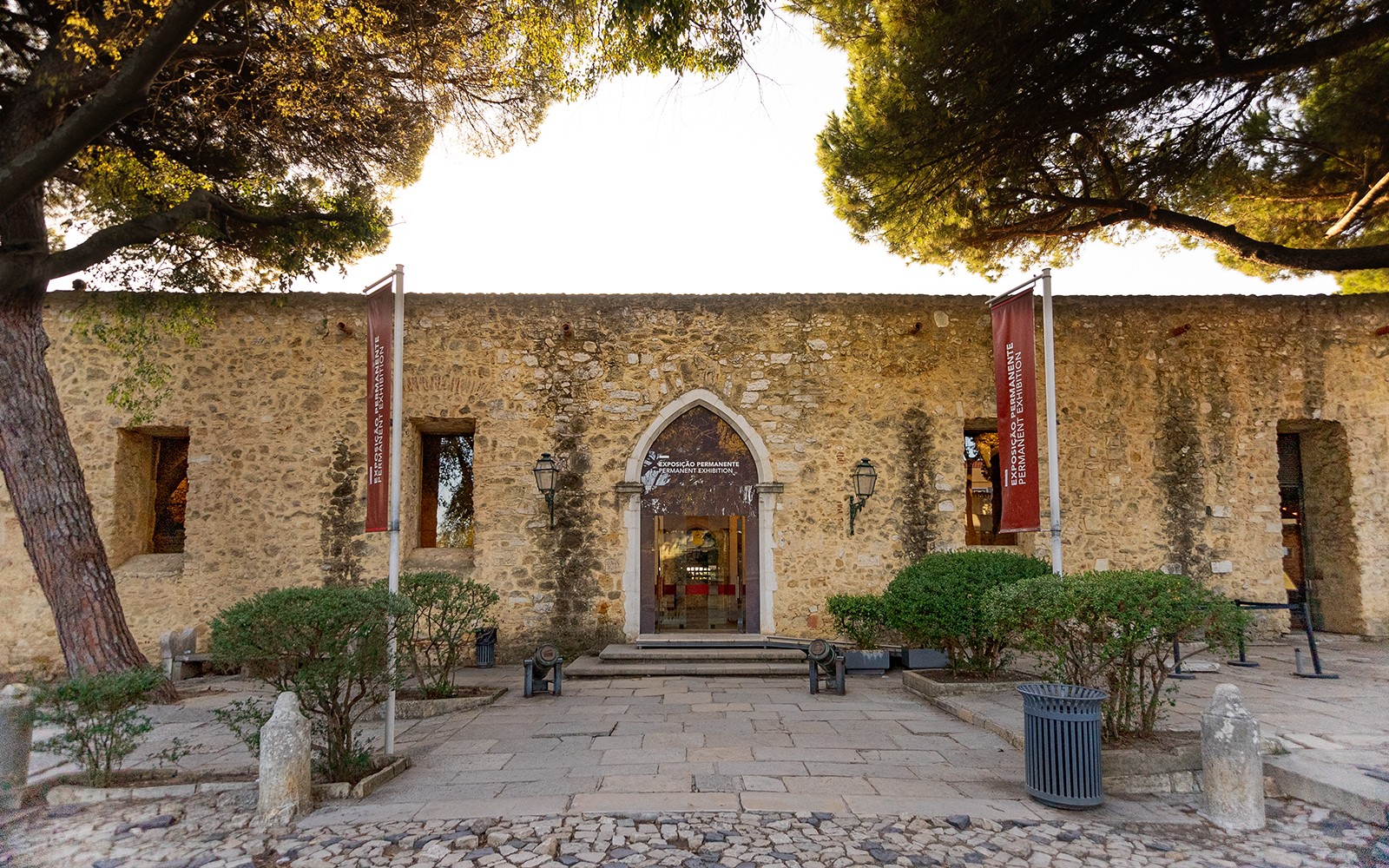 进入位于里斯本圣乔治城堡的常设展览,城堡拥有石墙外观和旗帜装饰。