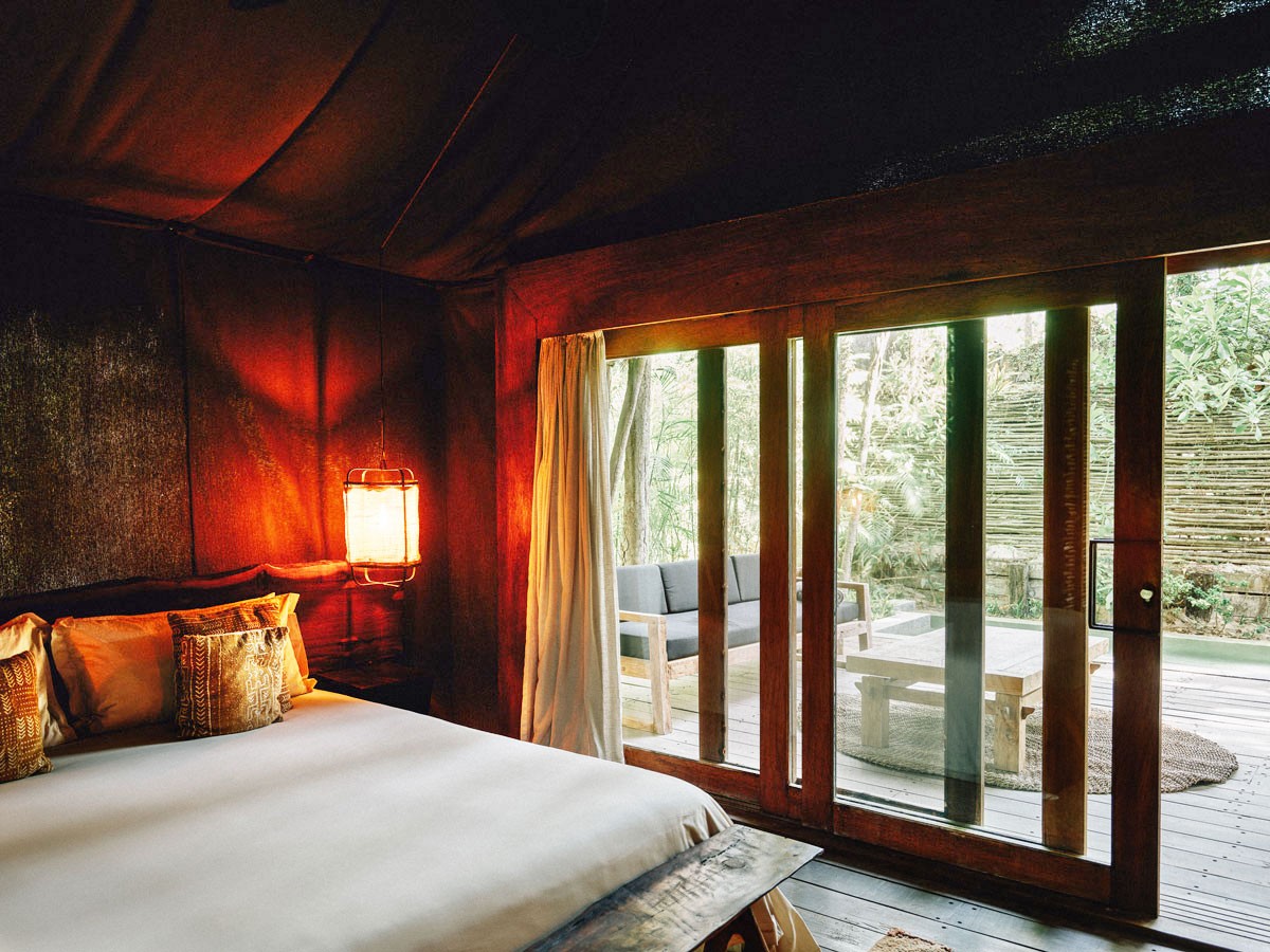 Deluxe Tent at Nômade Tulum highlighting rustic shower, sink, and large mirror with jungle-style decor.