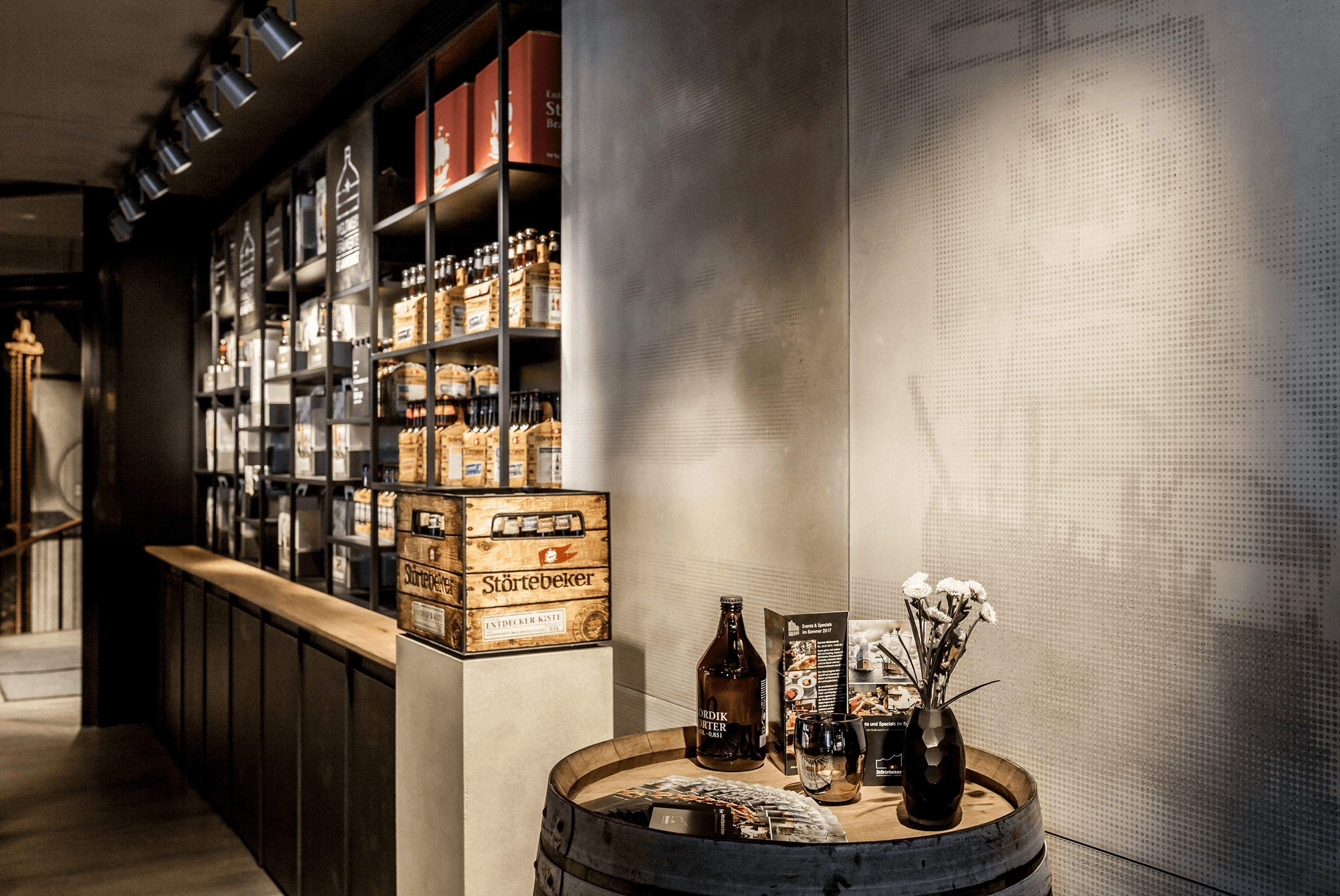 Beer bottles, crates, and flowers on a barrel display