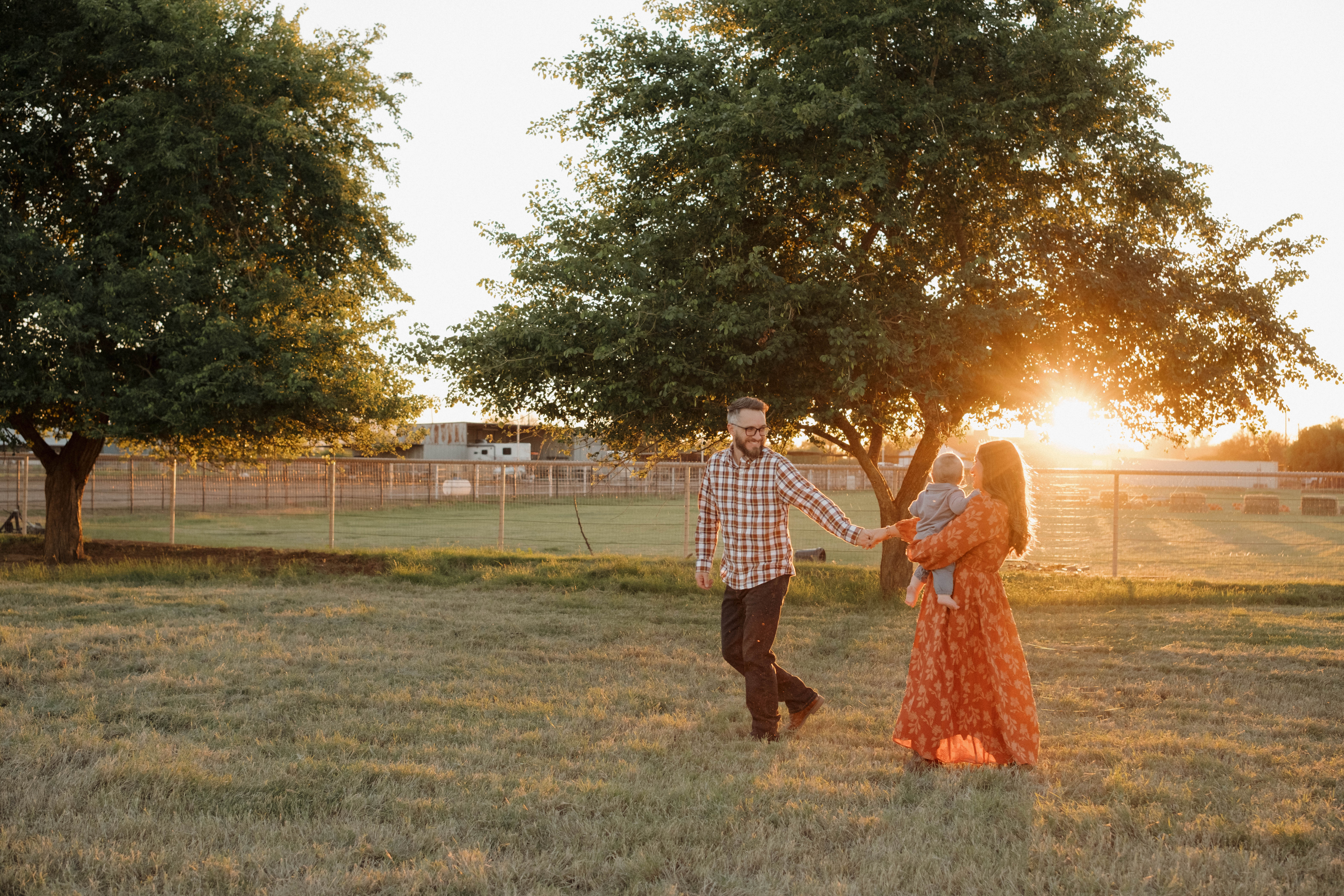 Photographer Ashley in a brown cowboy hat holding a camera, surrounded by a lush arrangement of white, pink, and orange flowers like peonies, garden roses, and gypsophila, in a bright studio in Gilbert, Arizona.