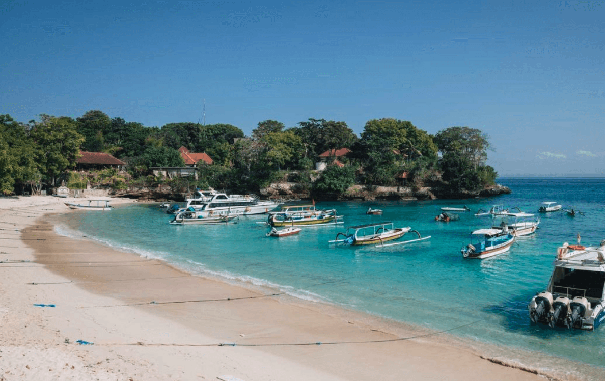 Turquoise waters and traditional wooden boats on the beach of Nusa Lembongan, Indonesia