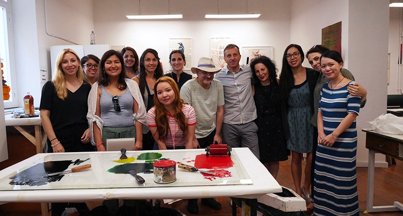 Students behind a white table with different paint color samples on it, used for making posters.