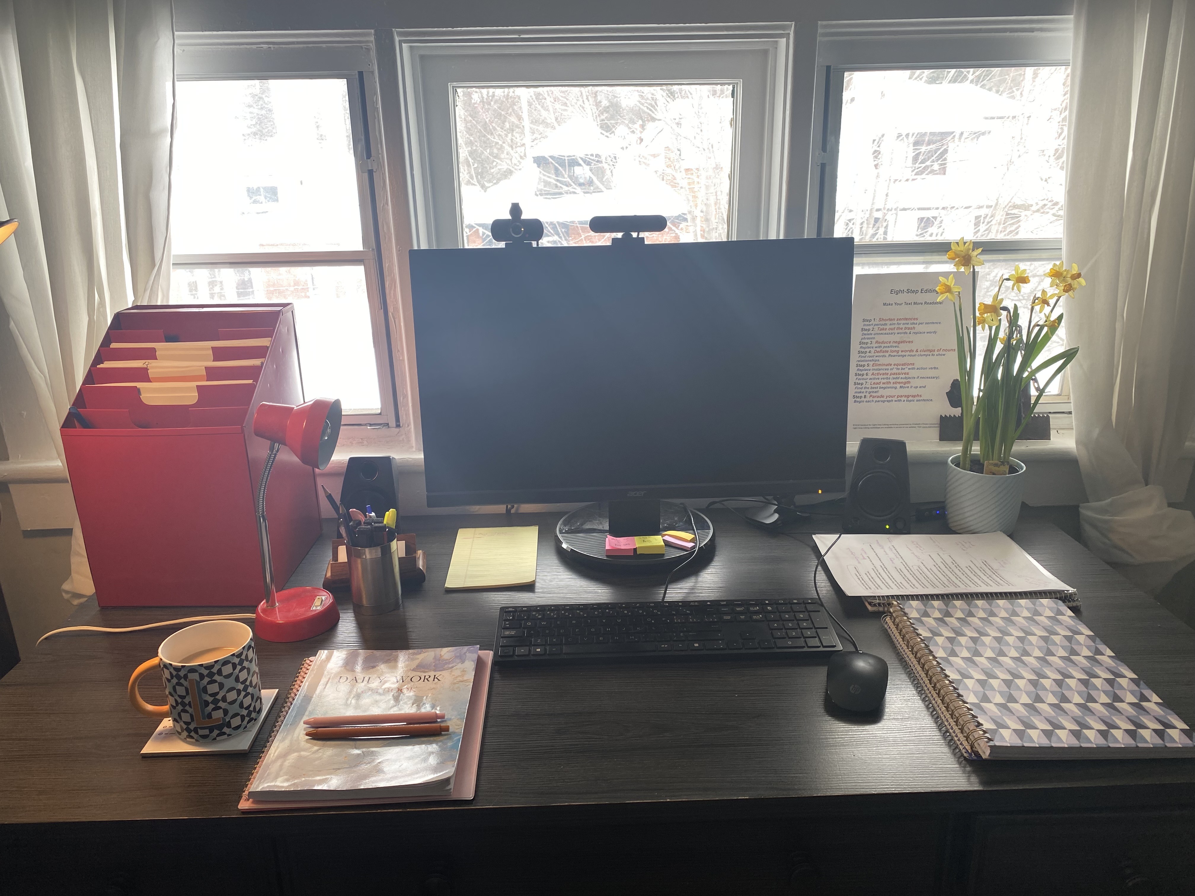 Brand strategy workspace with organized desk, computer monitor, planner, and notebooks.
