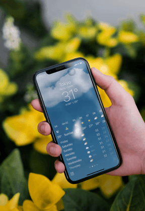 Person checking a weather forecast on a smartphone, representing route planning and safety awareness for truck drivers.