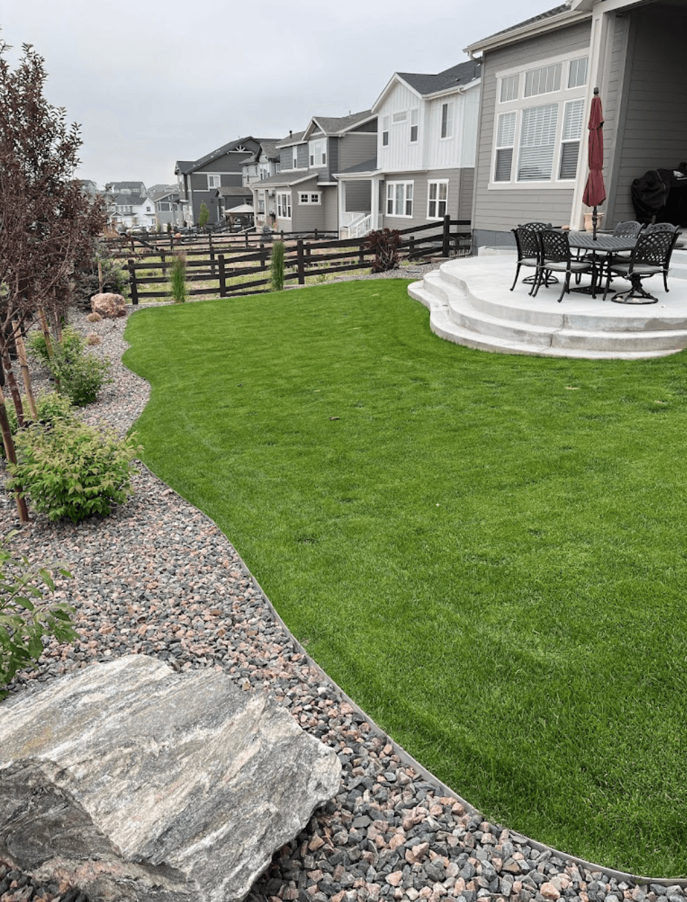 beautiful artificial grass in the backyard of a Colorado home, with small rocks and pebbles around it