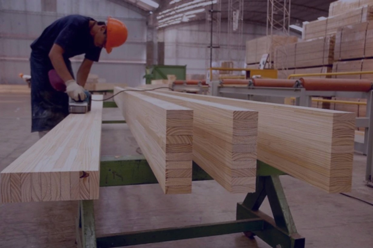 Image of a man snading down some wood in a warehouse