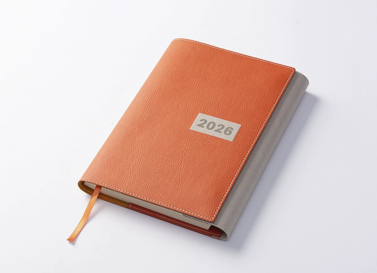 Tan and grey two-tone leather 2026 journal with ribbon bookmark, angled view on white background