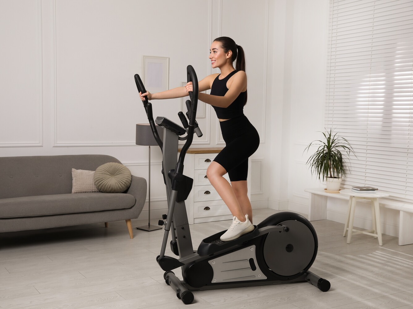 woman using an elliptical at home to complement her StairMaster workouts to lose weight at the gym