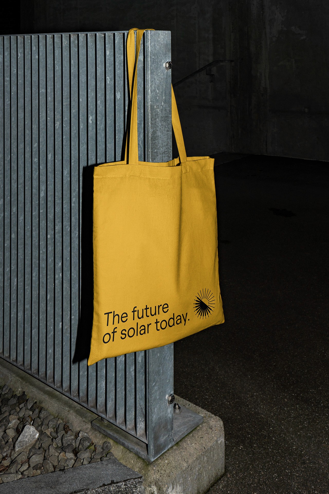 A bright yellow canvas tote bag hanging on a metal fence, featuring the Aurora Solar logo and the tagline "The future of solar today." This brand collateral design showcases how the studio translates a digital mission into physical, sustainable marketing assets.