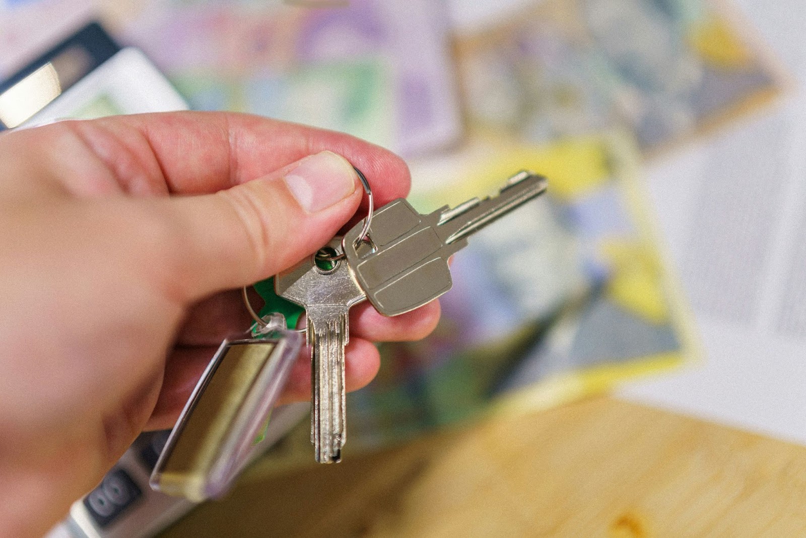 Someone holding keys above a desk with cash on it