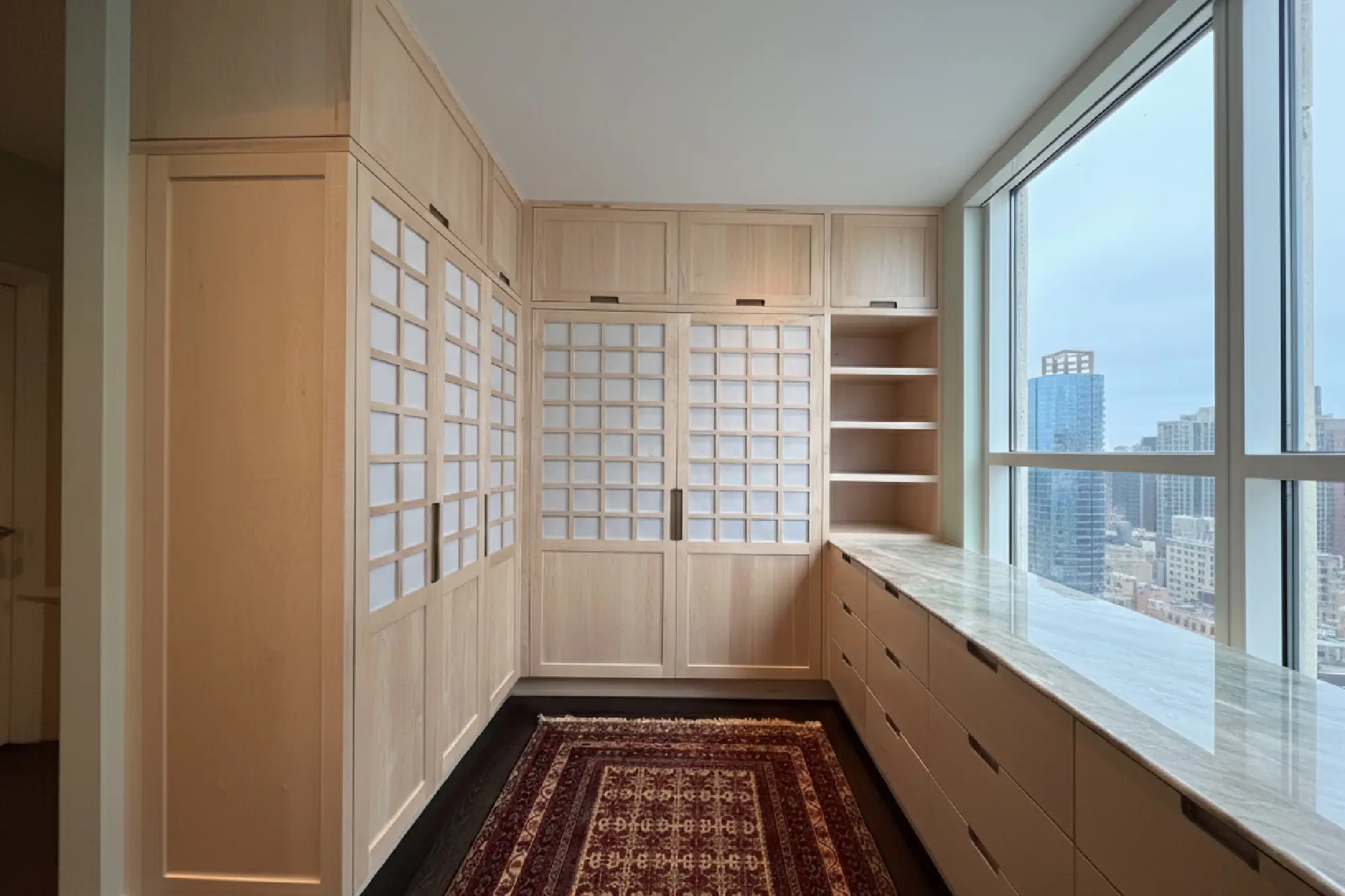 Walnut closet with shoji-inspired backlit panels and Persian rug in a downtown high-rise dressing room, Austin