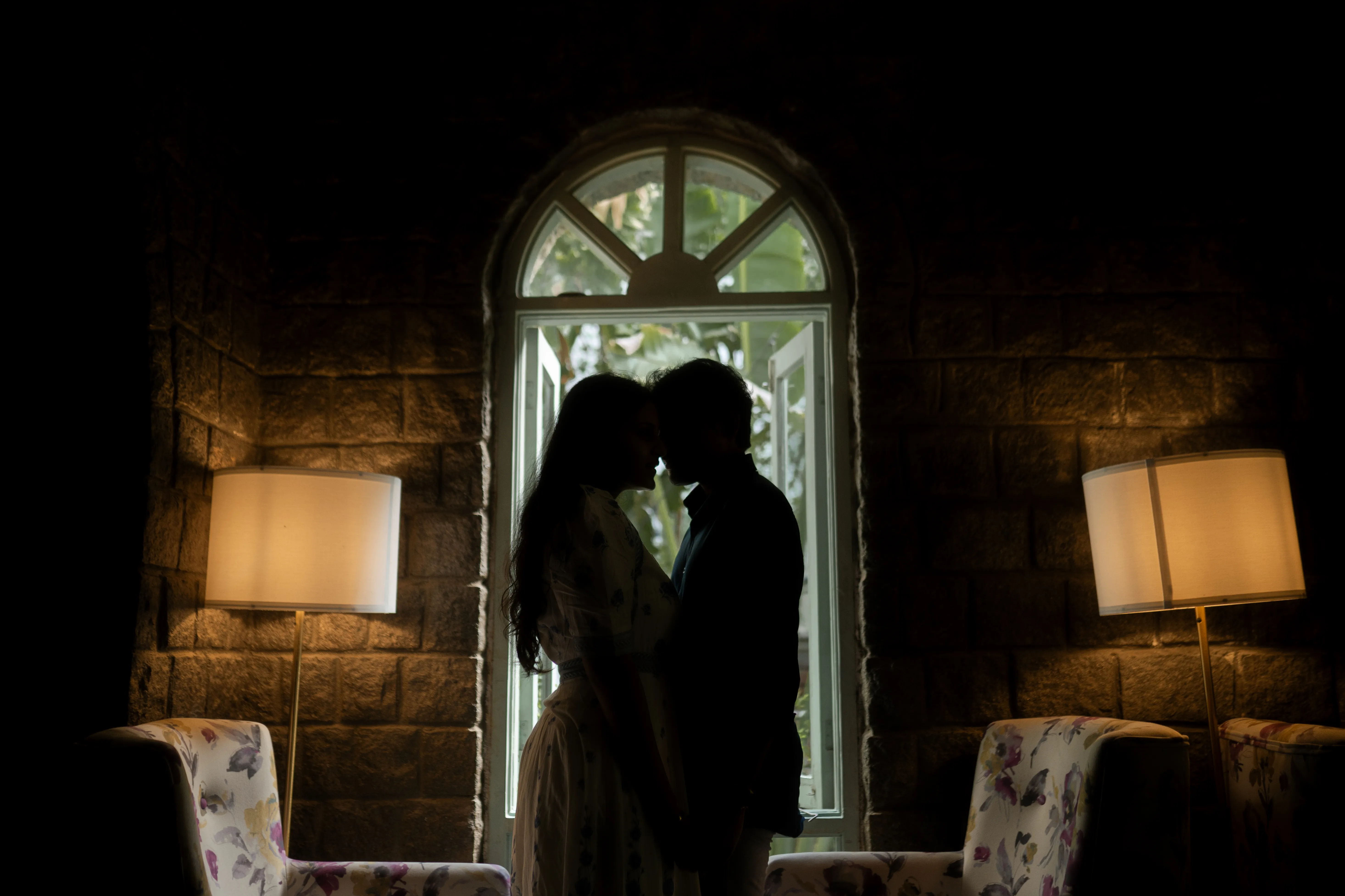 Tanya and Jashwanth share a passionate kiss by a window in a cozy cottage. Captured by Out of The Blues Fine Art Wedding Photography in Hyderabad.