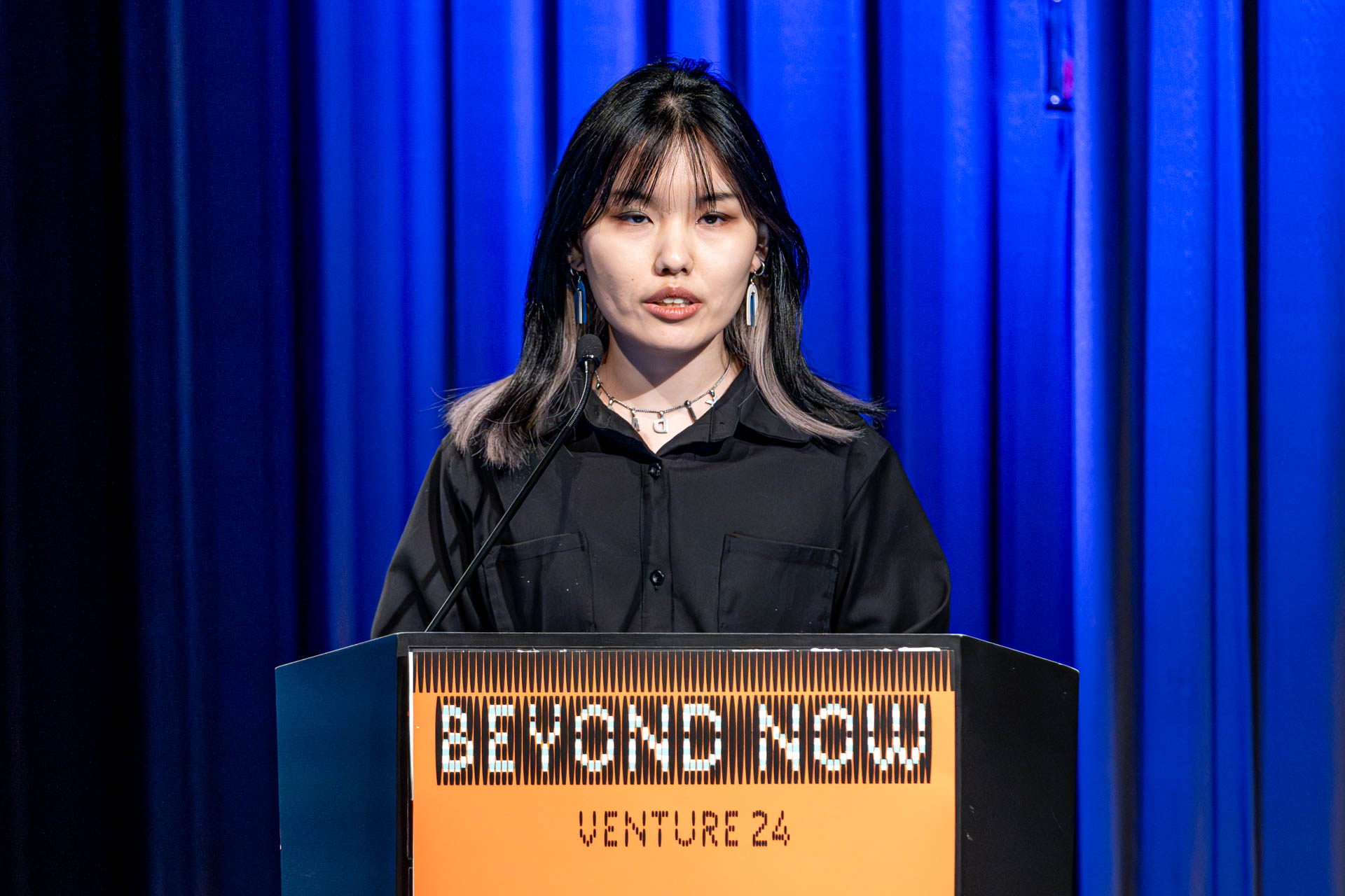 a student at a podium presenting a project in a Theatre