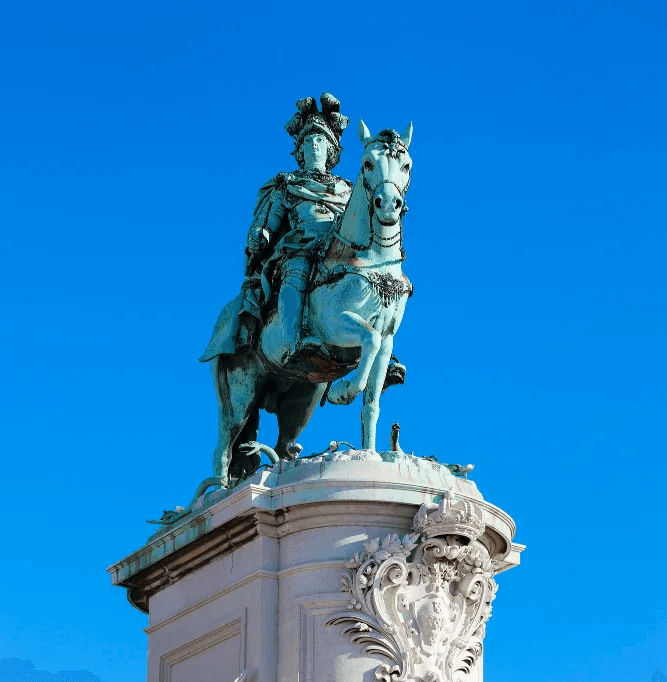 Estátua histórica em praça de Lisboa com céu azul ao fundo