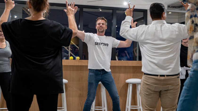 Group of people participating in an exercise class, with one person demonstrating movements.