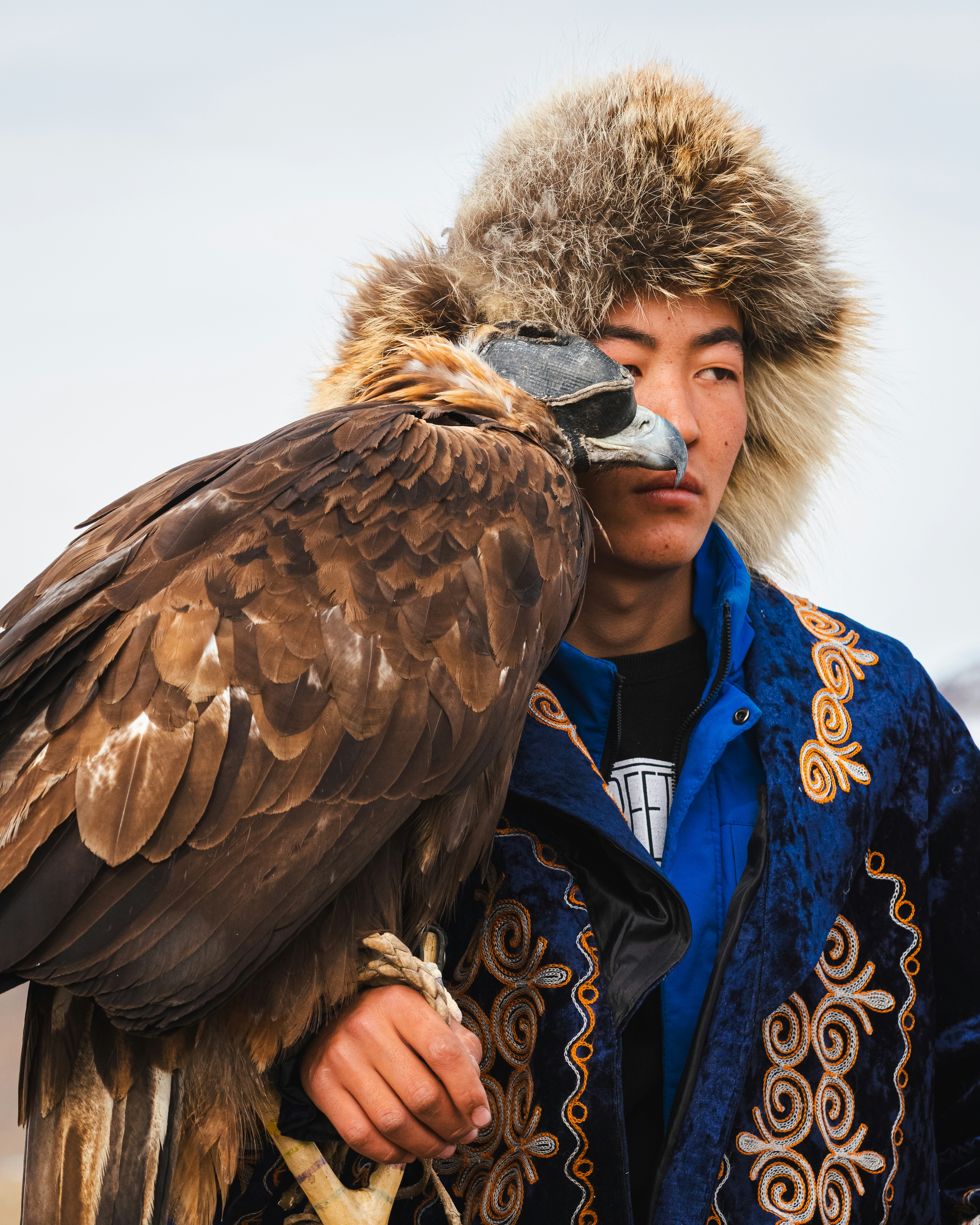 A man and his eagle look stoically ahead.