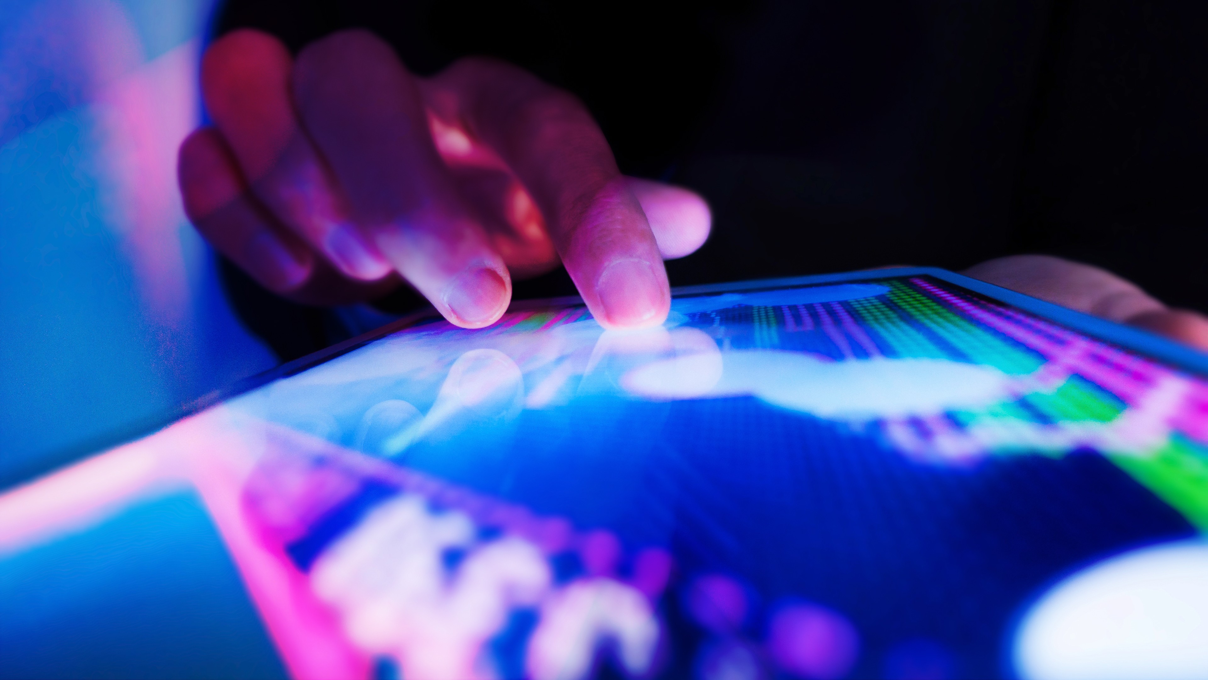 A hand touching a touch-screen on a tablet