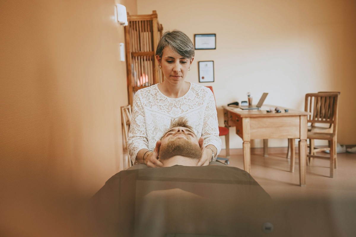 Mathilde Hérault-Moreau, chiropracteur, effectuant un ajustement cervical sur un patient, les mains placées sous sa tête, pour corriger l’alignement vertébral et améliorer le bien-être général dans un cabinet de consultation.