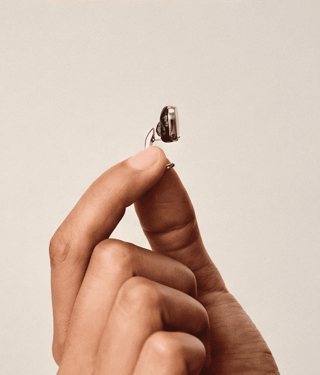 Product close-up of a hand holding a metallic wireless earbud