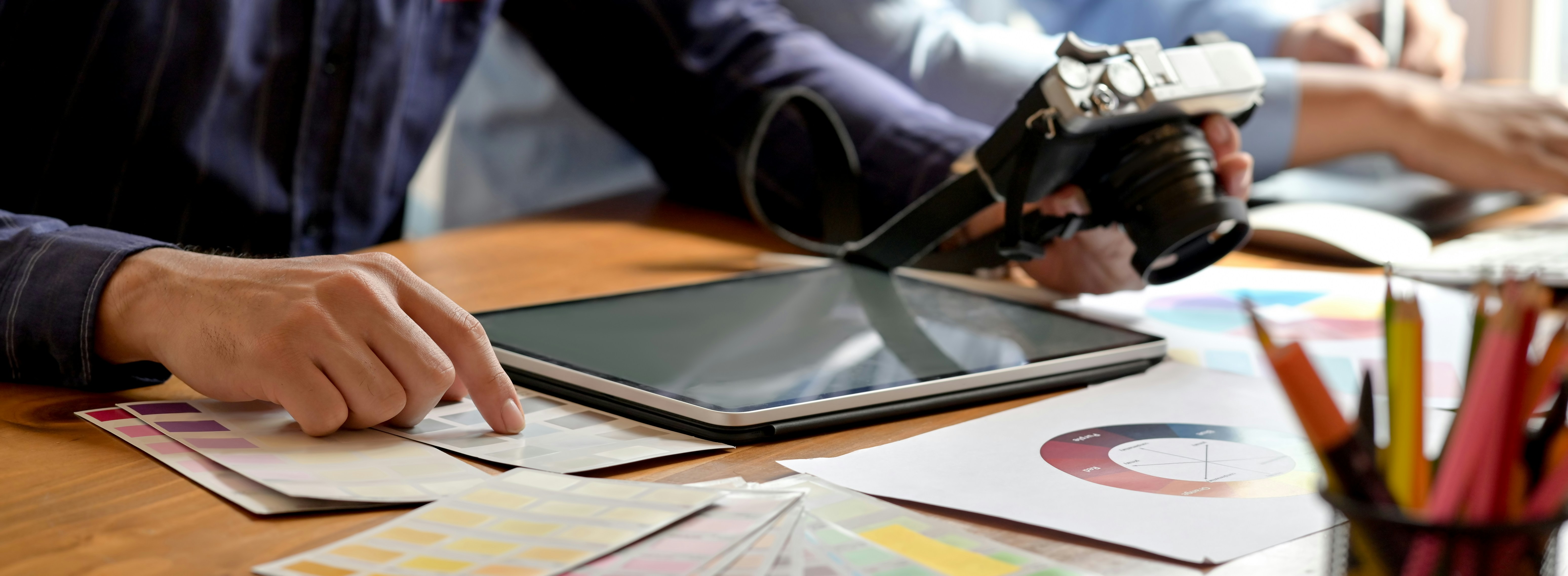 A person holding a camera is silhouetted against vivid orange stage lights. The scene conveys focus and creativity with a dramatic, moody atmosphere.