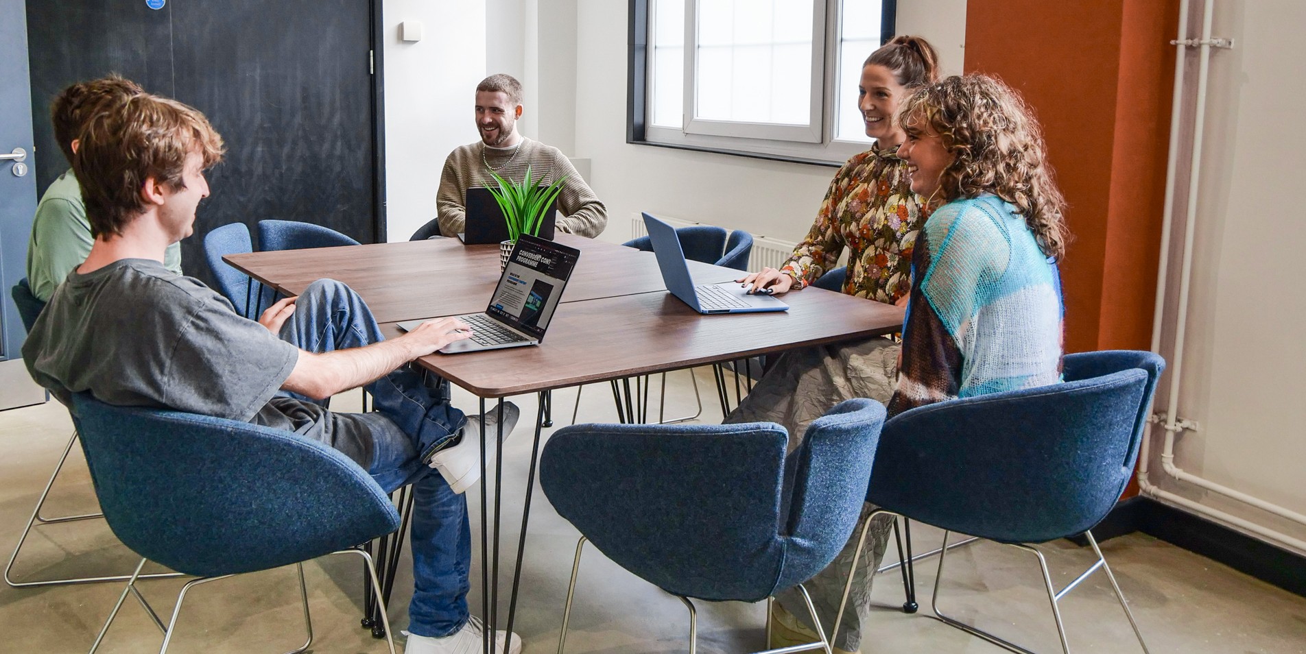 People sitting around a table using laptop computers.