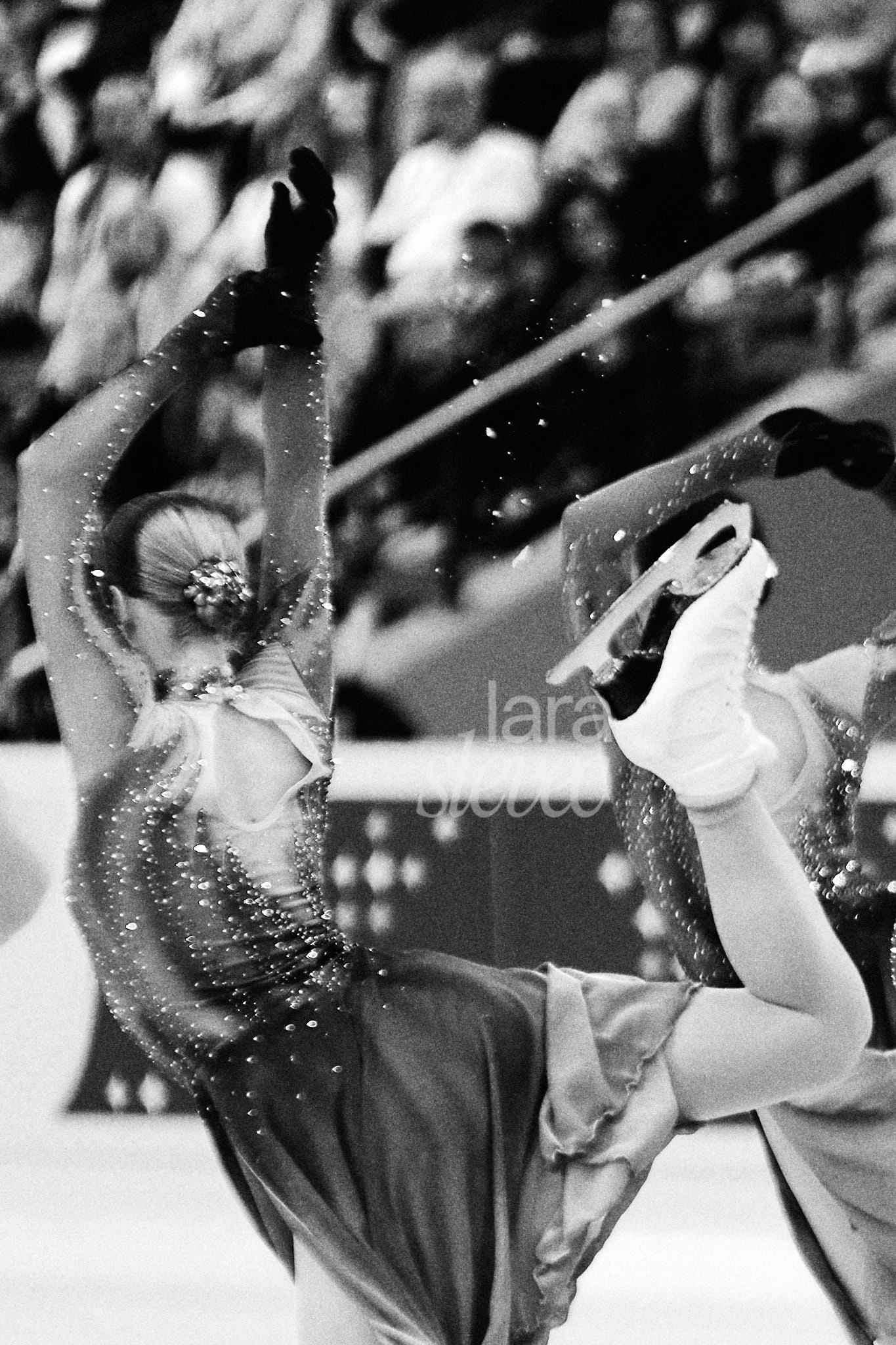 Schwarz-Weiß Fotografie einer Eiskunstläuferin, die gerade ihre Arabesque loslässt. Man sieht Eis in der Luft. Team Haydenettes. ISU Synchronized Skating Championships 2026 in Salzburg. Fotografiert von Lara Slevec.