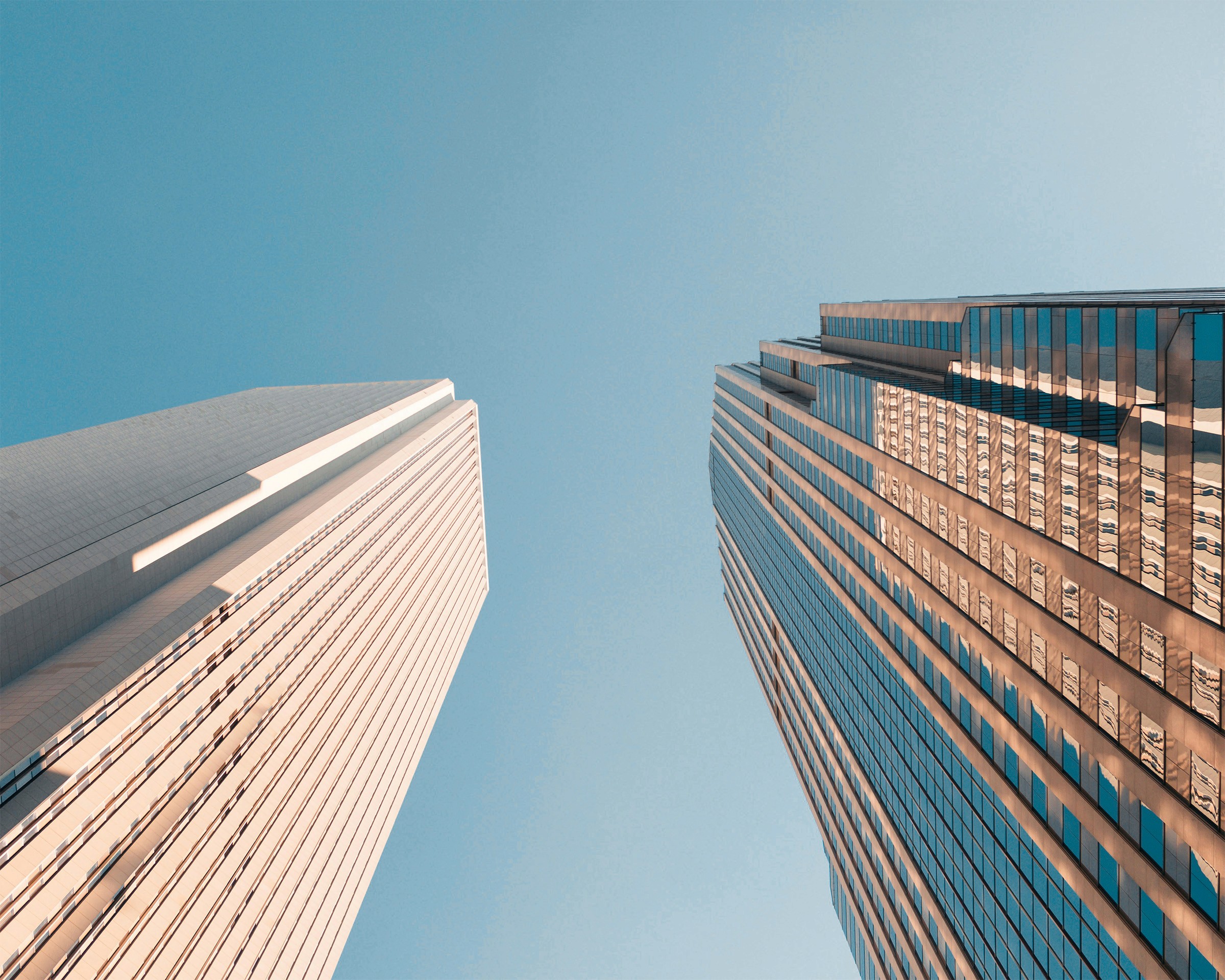 Tall modern skyscraper with vertical lines, viewed against a clear blue sky.