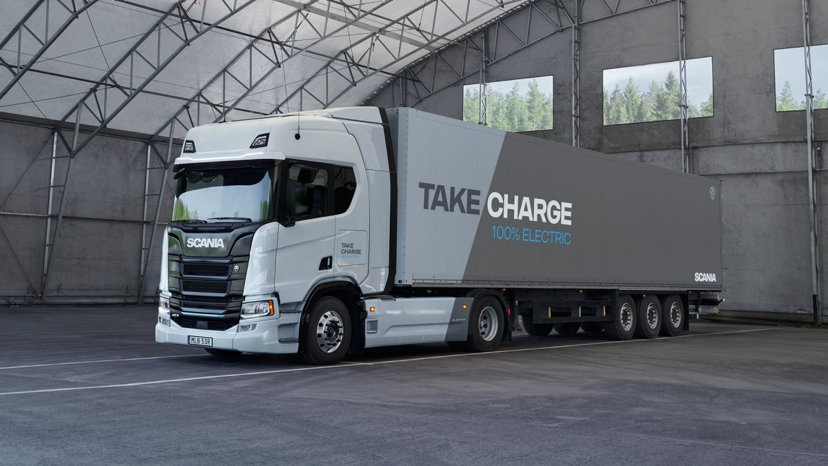 Camion électrique Scania avec le slogan 'Prenez Charge – 100% Électrique', mettant en avant la transition vers des solutions de transport de marchandises durables et zéro émission en Suisse.