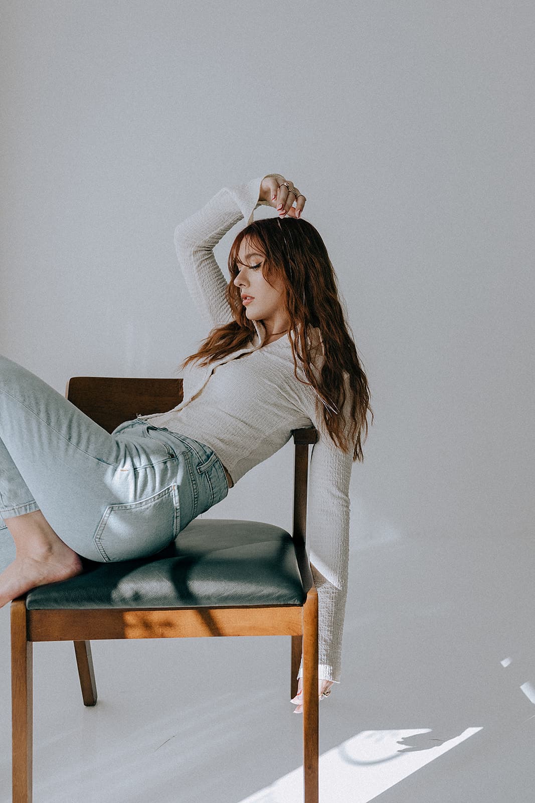 A model lounges effortlessly on a chair in the sun-drenched Revelator Studio in Shreveport, a natural light photography studio ideal for creative and professional photoshoots.