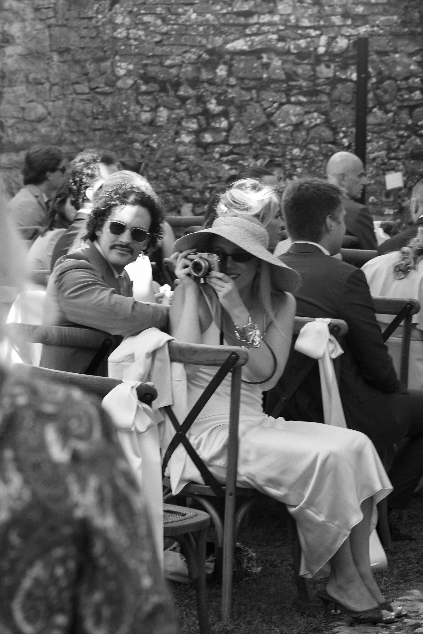 Ospiti seduti al ricevimento nel giardino del Castello di Scipione, atmosfera intima tra muri medievali e luce naturale
