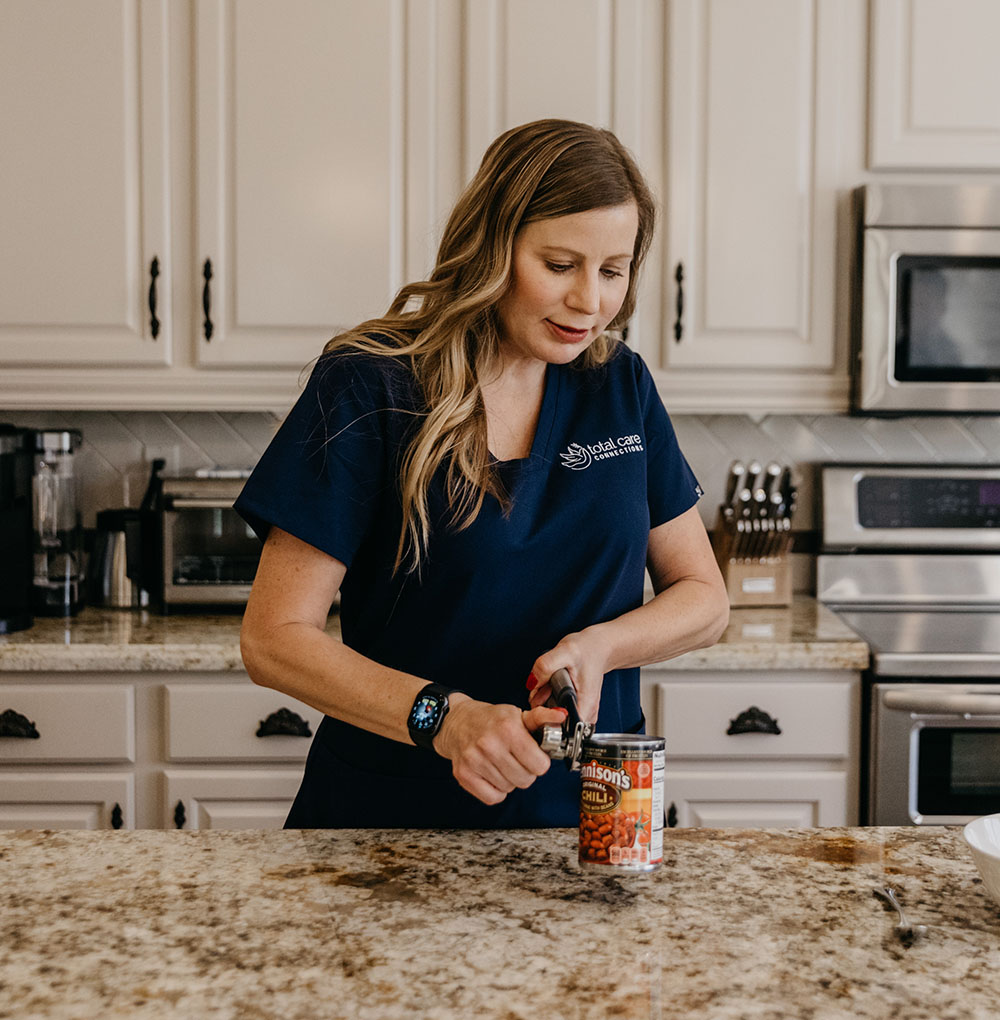 Care worker opening a can of food in client's kitchen.