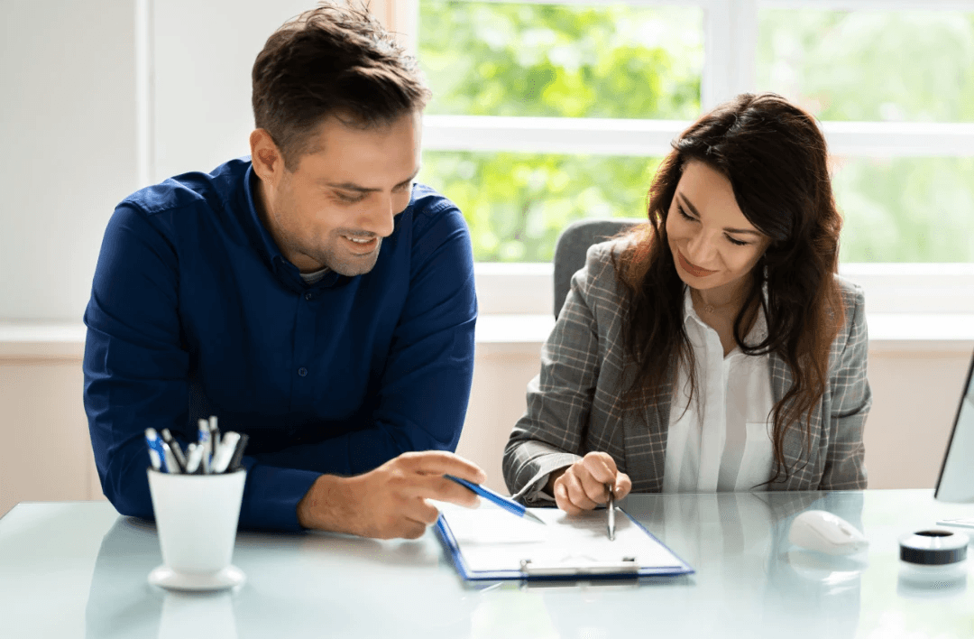 Persons discussing real estate with laptop, documents, and model of commercial  property