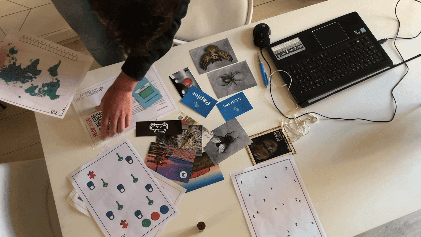 Persoon legt verschillende puzzelstukken en kaartjes op tafel tijdens een Remote Teambuilding spel van The Box Company.