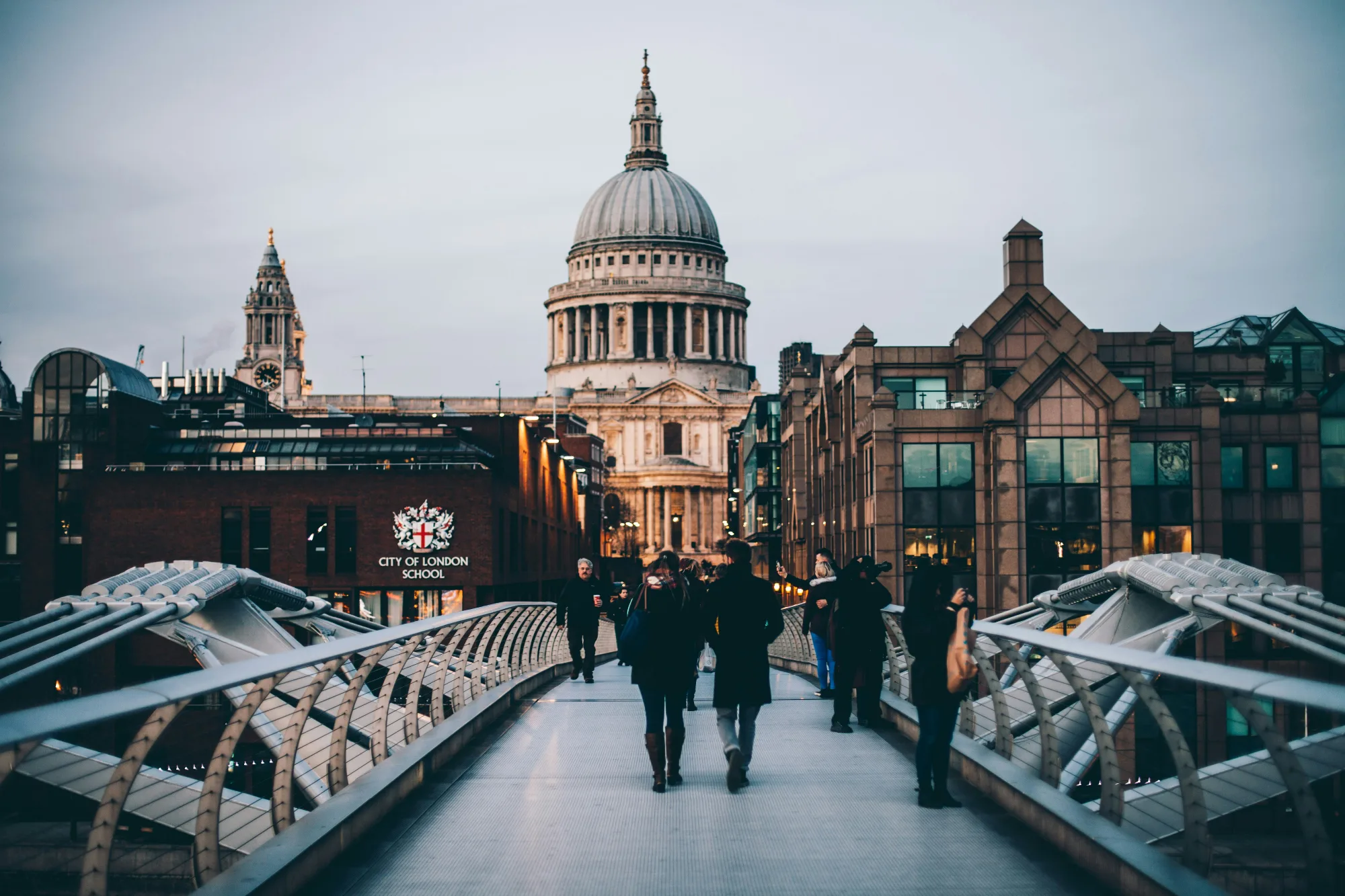 People walk across the Millennium Bridge towards St. Paul's Cathedral in London.