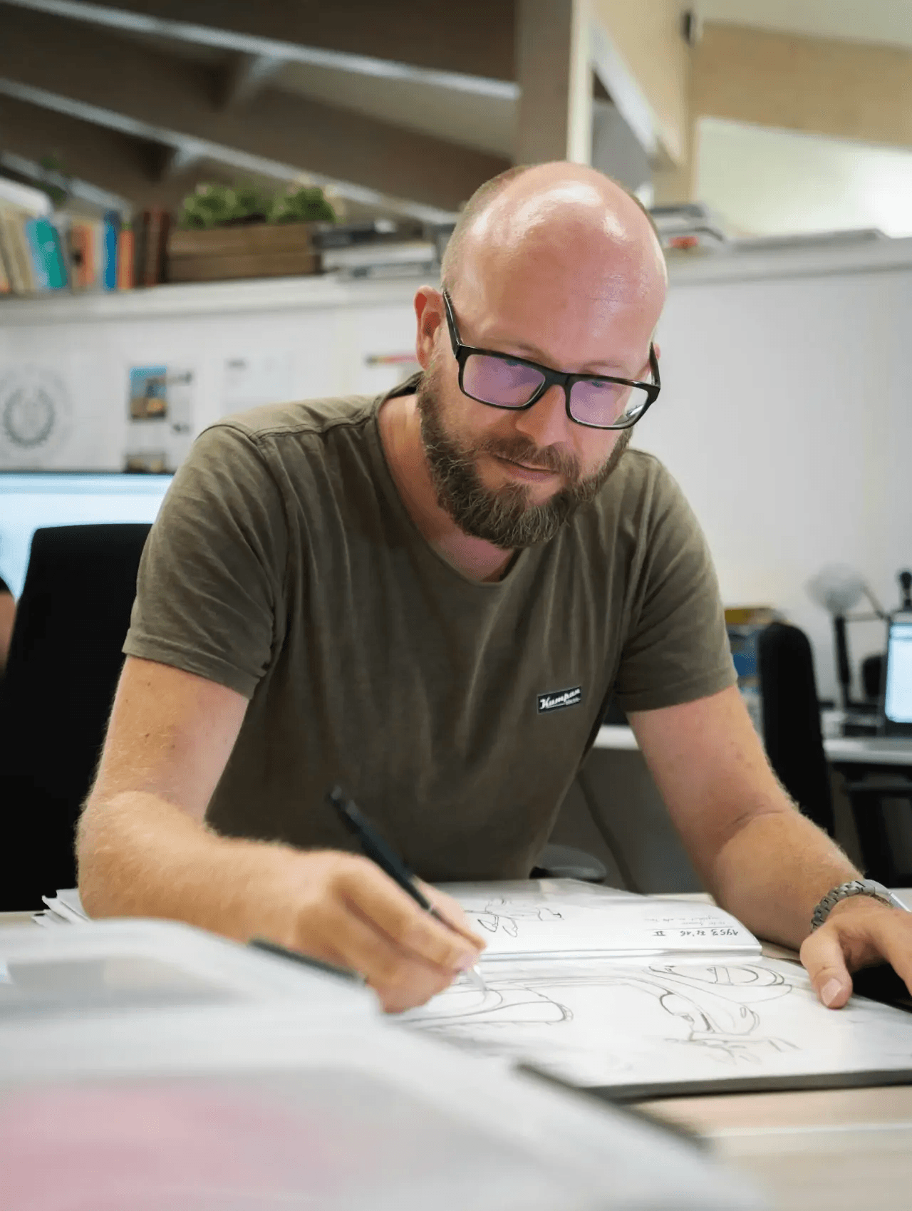 Man drawing technical plans at a workbench