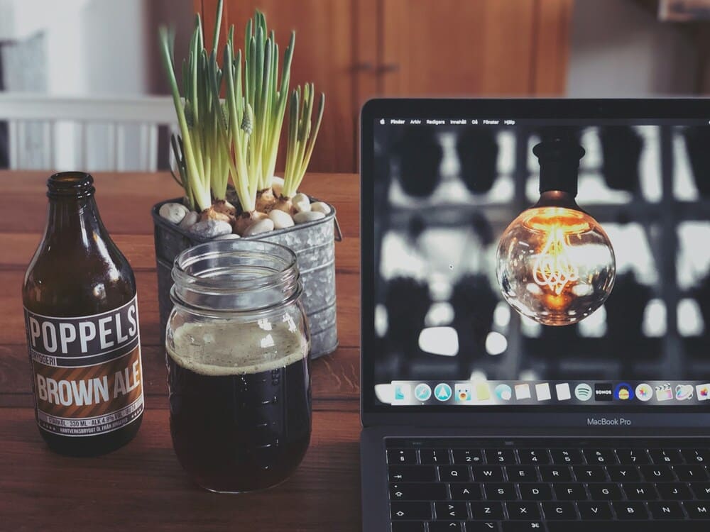 Imagem de destaque, garrafa de cerveja, copo com cerveja ao lado de um notebook