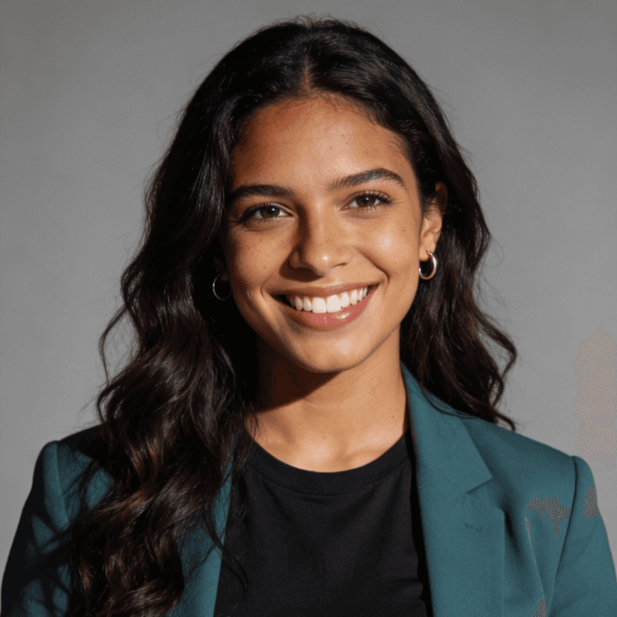 A smiling woman dressed in a green blazer over a black shirt poses confidently.