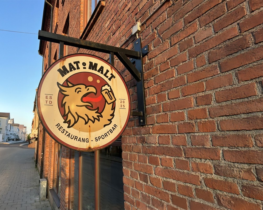 Circular Mat & Malt logotype mounted on a red brick wall, showing brand identity work by OUF Studio.
