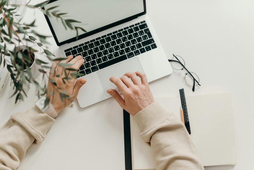 Human typing on laptop on white desk