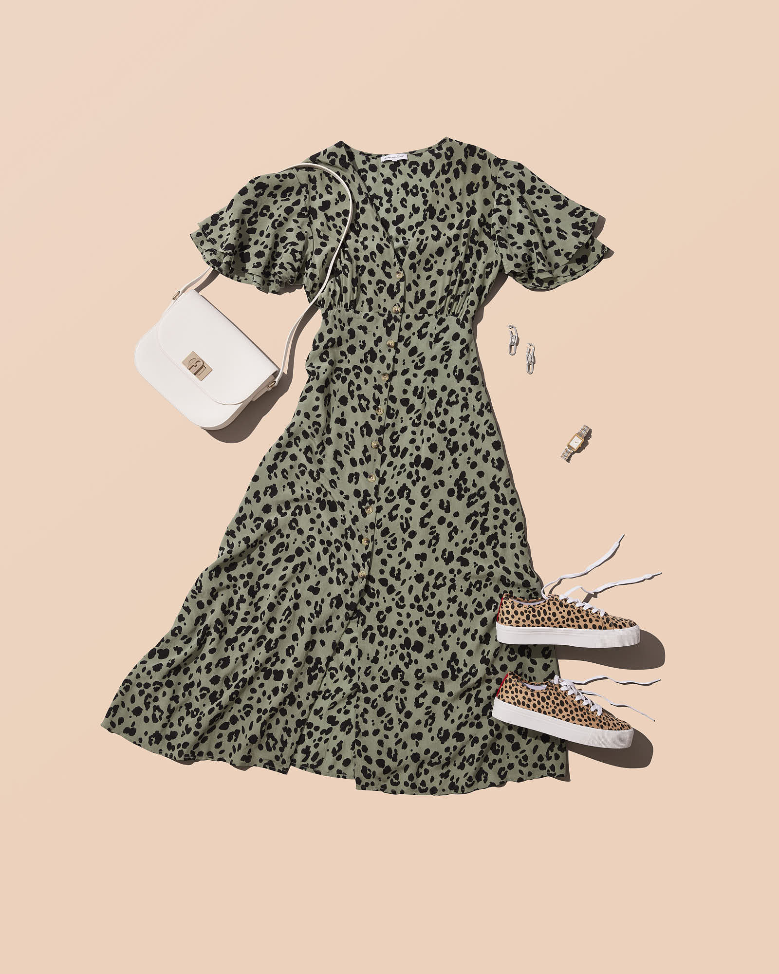 Leopard print dress with white handbag, stylish earrings, watch, and matching sneakers on beige background.