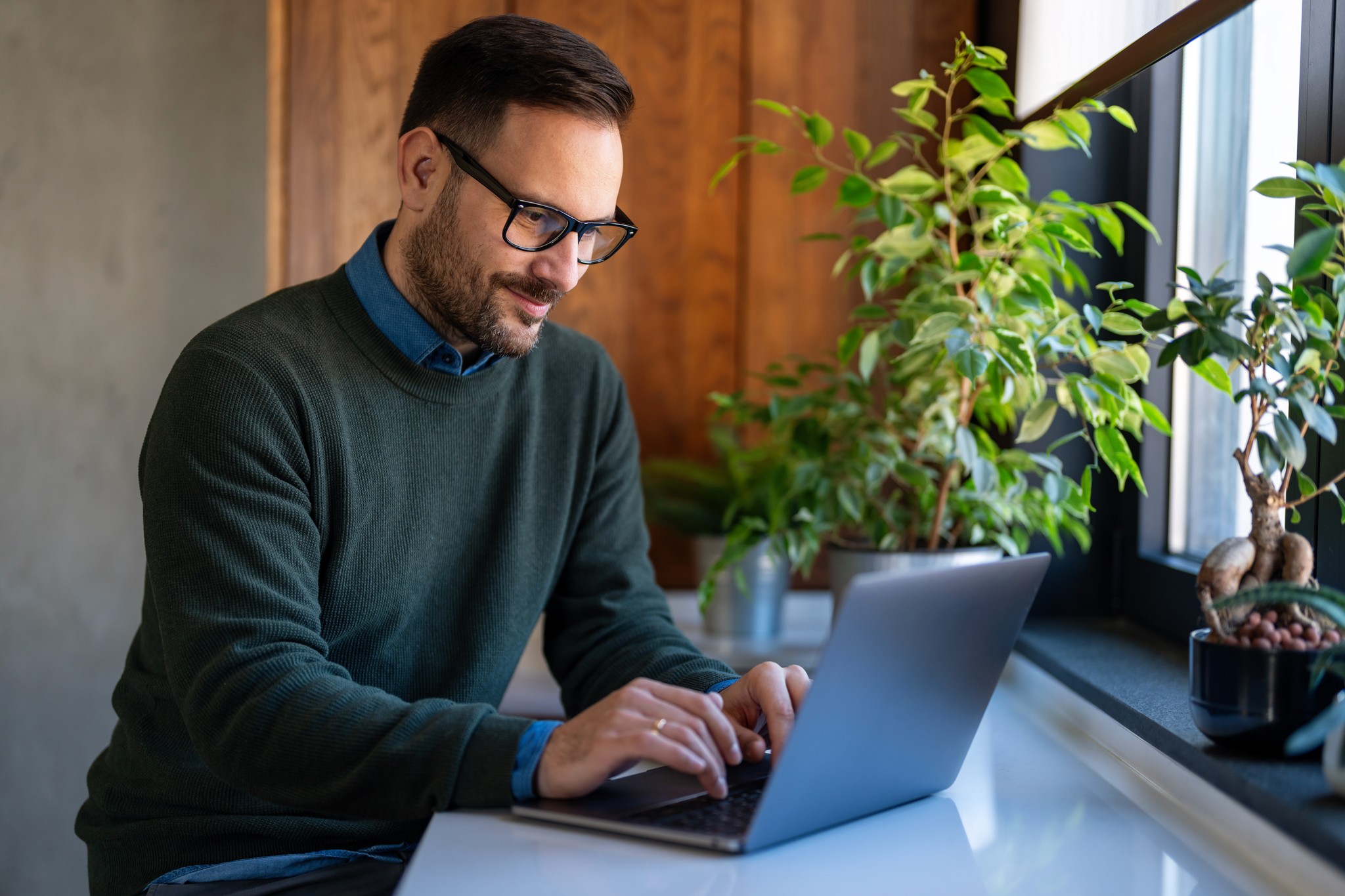 A winding road cuts through rocky terrain, surrounded by patches of green grass and illuminated by sunlight.