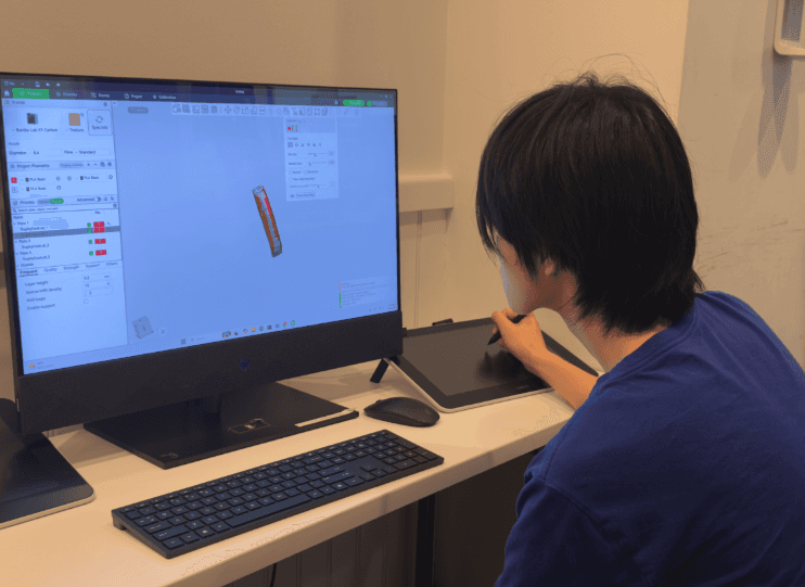 Teen uses a drawing tablet to design a 3D trophy.