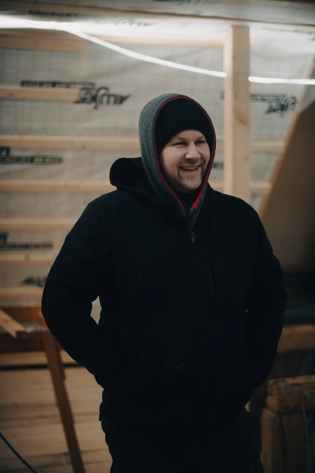 Patrick Levsen von der Zimmerei Levsen ist auf einer Baustelle und lächelt in die Kamera