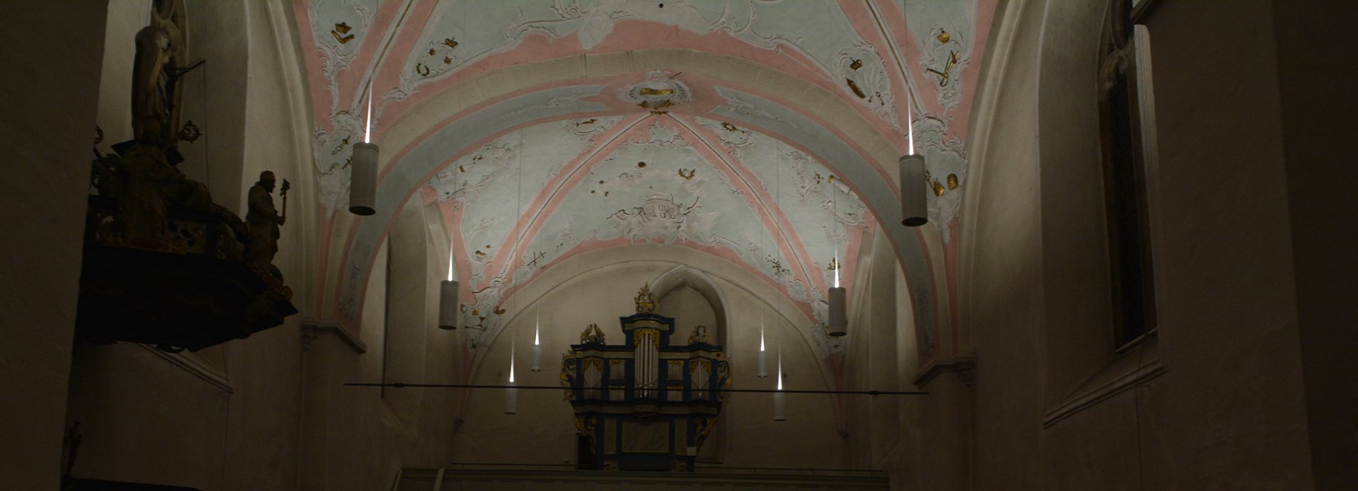Innenansicht einer alten Kirche mit Gewölbedecke, Deckenmalerei und Kerzen. Stimmungsvolle Aufnahme einer Kirche.