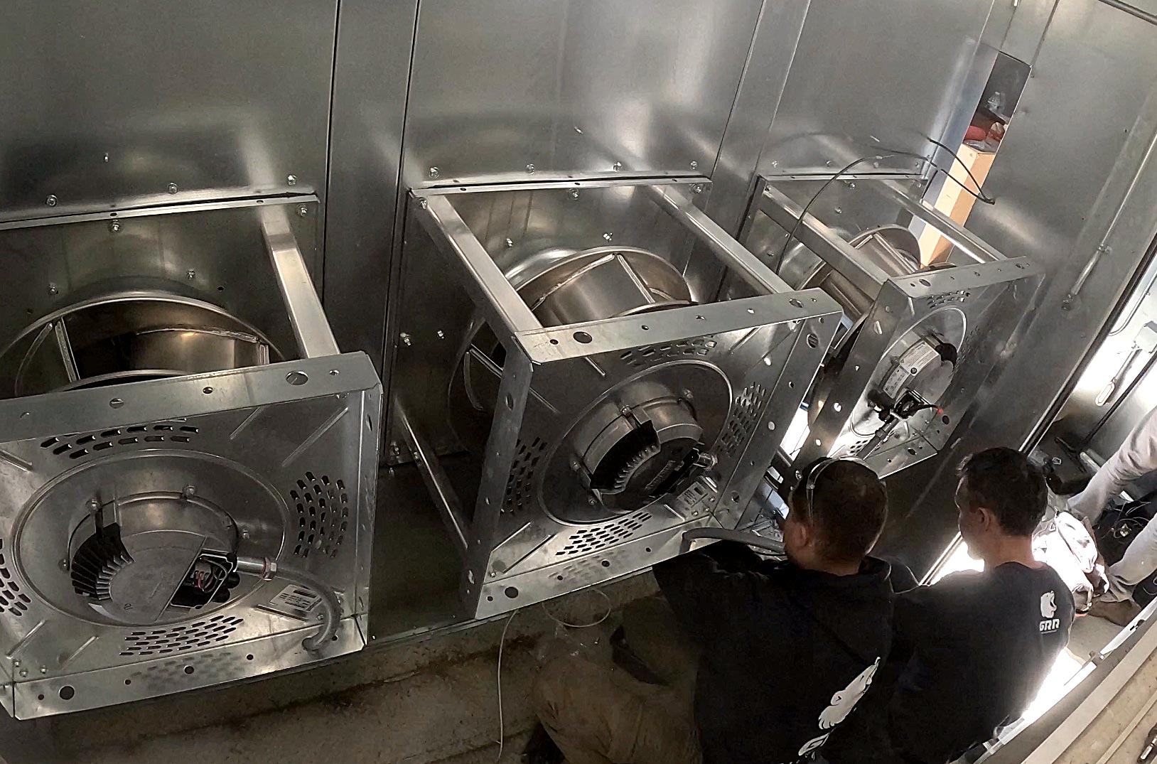 GRR Cooling Experts technicians installing and commissioning an HVAC fan array inside a commercial air handling unit in New York City.