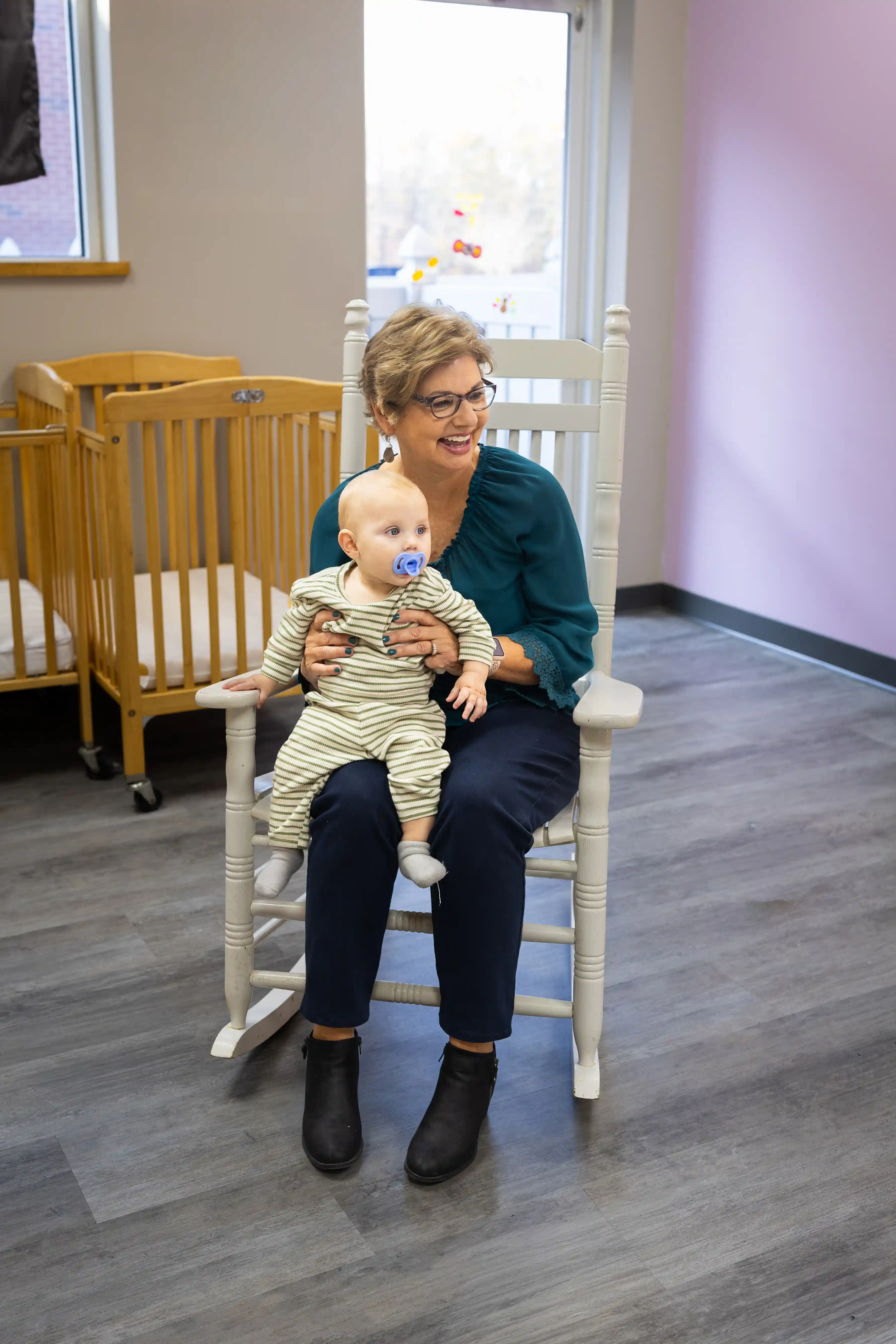 Nursery volunteer smiling with baby