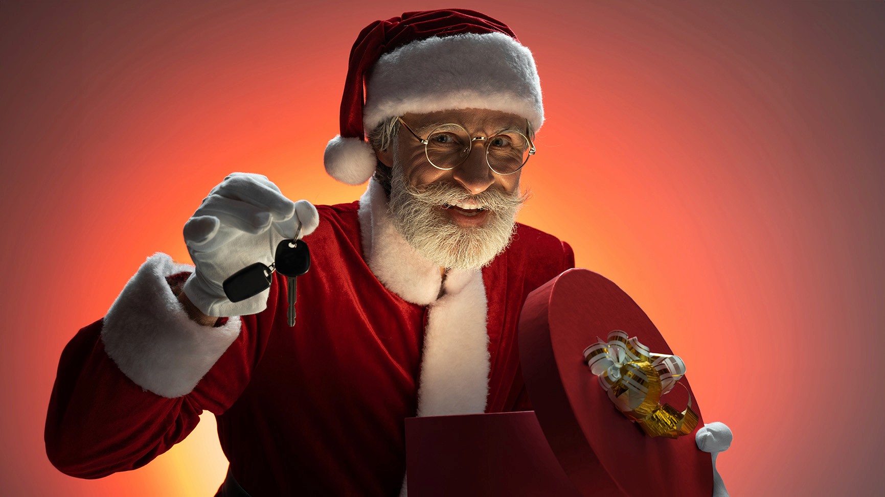 Mężczyzna przebrany za Mikołaja trzymający kierownicę i kluczyki.