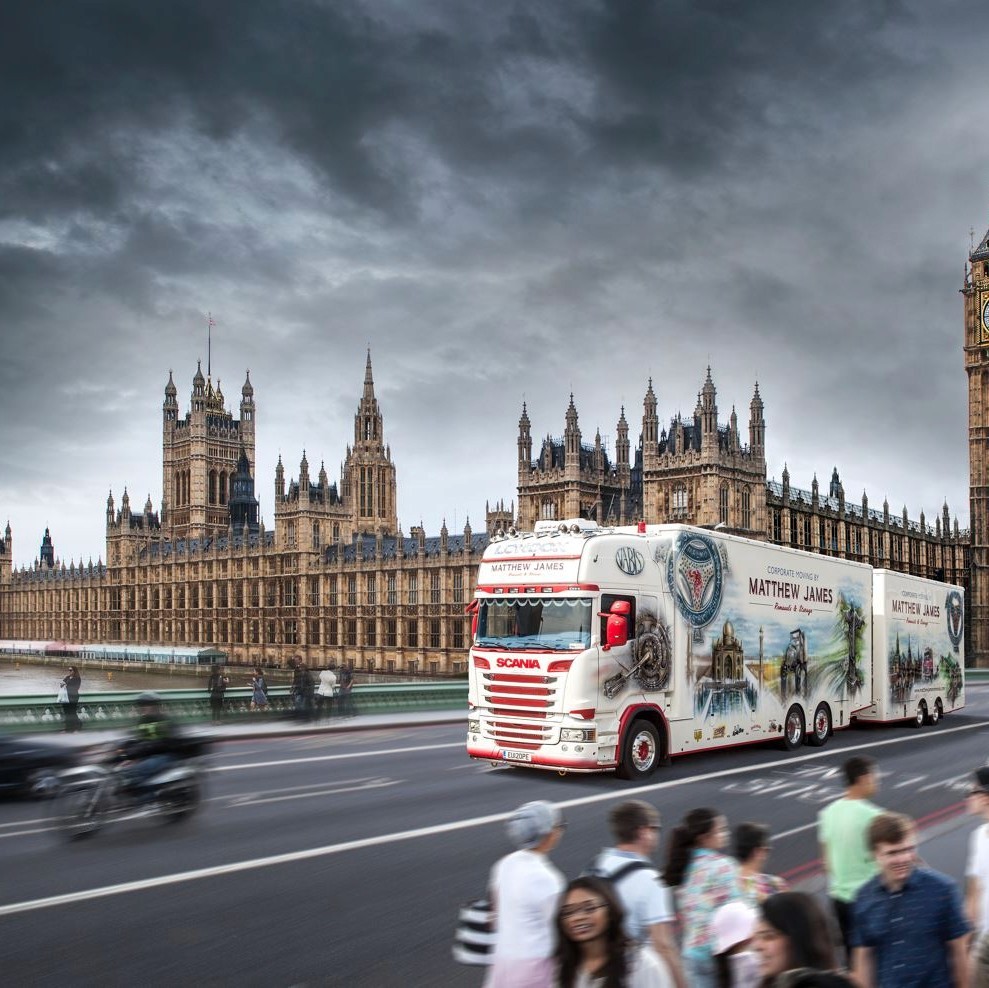 A commercial truck driving in London under a "Low Emission Zone" sign, illustrating the city's stricter emission standards for vehicles.