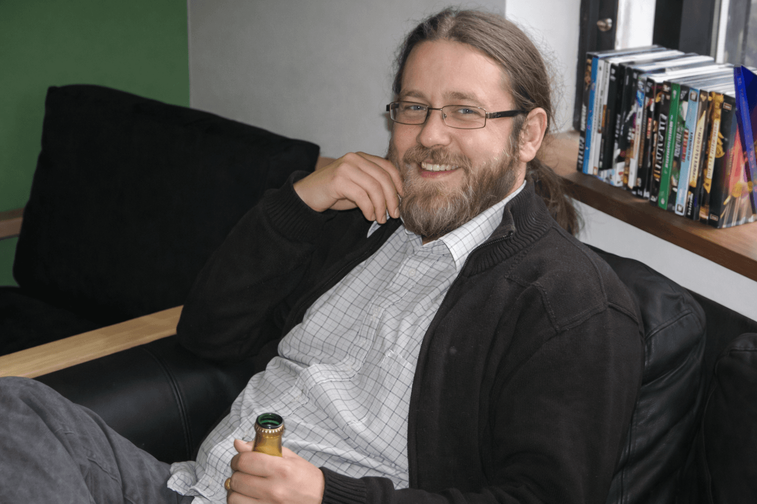 Green microscopic organism with textured surface and smaller structures surrounding it on a black background.