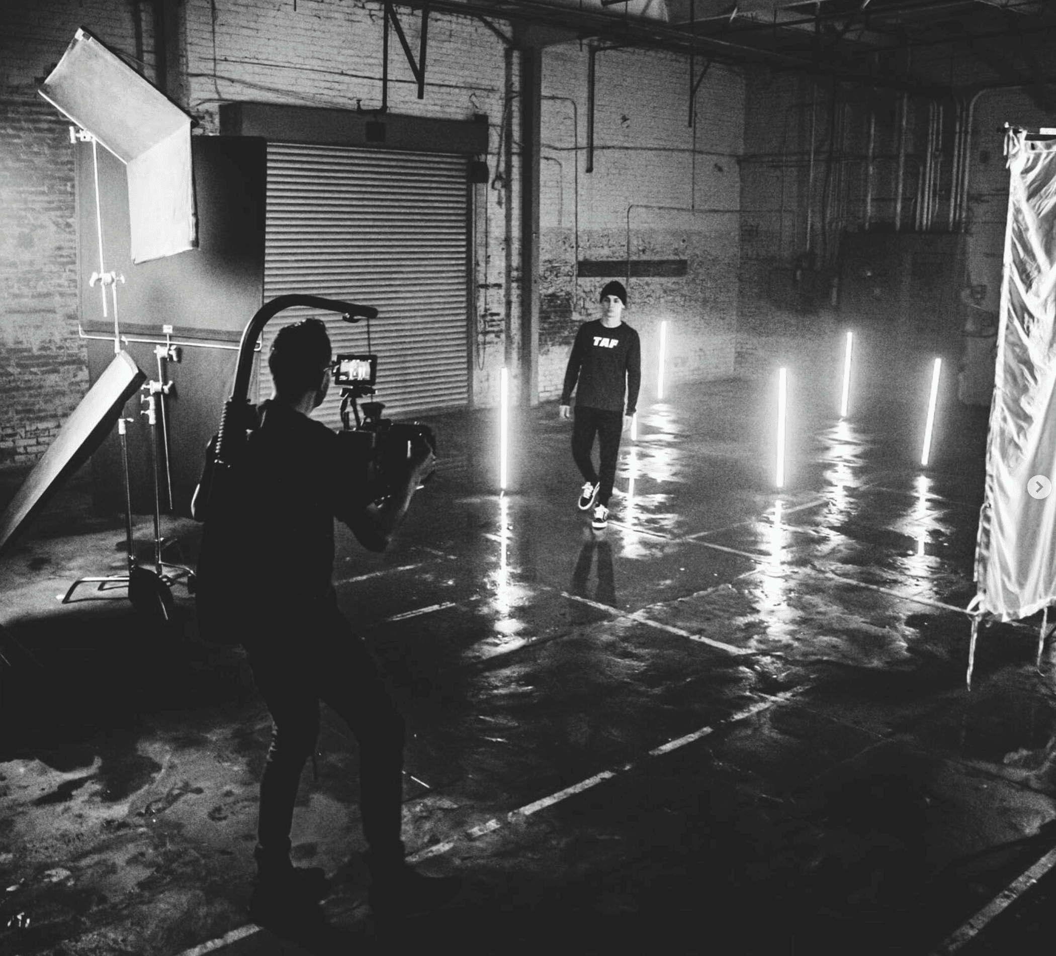 A large group photo of diverse team members gathered in an industrial-style space with arched ceiling.